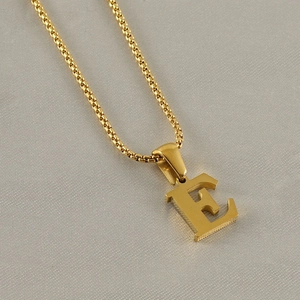 Detailed close-up of golden stainless steel ball chain necklace with letter E pendant