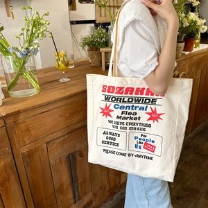Detail of cream canvas tote bag with retro American print worn over the shoulder
