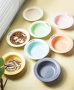 Top-down view of Morandi-colored ceramic cat bowls with dry food on a sunlit floor