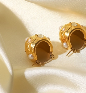 Gros plan sur une boucle d'oreille créole dorée 18K avec texture et perle d'eau