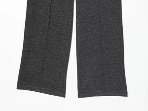 Detail view of dark grey trousers showing vertical ribbed texture and precise hem stitching