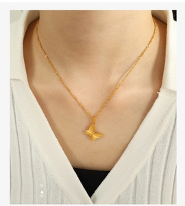 Close-up of golden butterfly pendant on water wave chain worn by a model