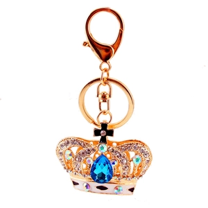 Golden crown keychain with sparkling blue crystal teardrop and rhinestones on white background