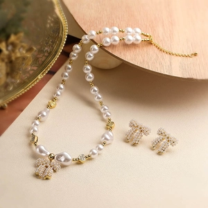 Detailed view of gold pearl jewelry set including bow earrings and heart charm necklace