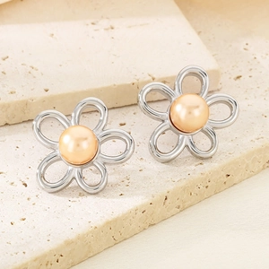 Macro detail of silver floral stud earrings with peach pearls on stone base