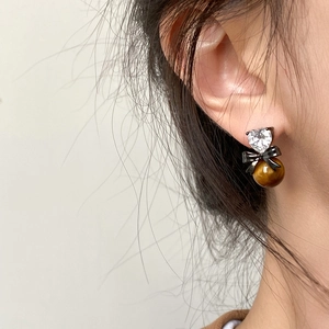 Retro tiger eye heart earrings with zircon and bow detail on female model