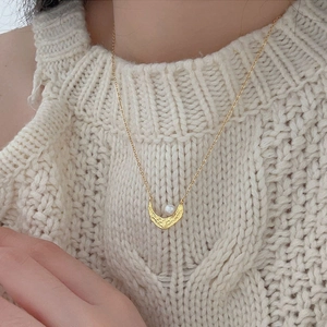 Detail of 925 sterling silver crescent moon pendant with pearl on a textured gold chain