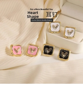 Dettaglio di orecchini a cuore in smalto placcato oro nei colori bianco, rosa e nero