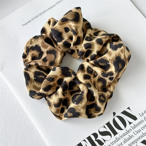 Close-up of leopard print satin scrunchie resting on a stylish magazine background