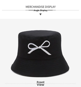 Detail of black cotton bucket hat featuring white bow embroidery and high-quality fabric