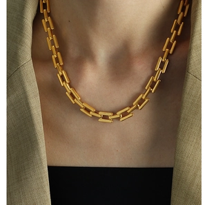 Detail of chunky 18k gold plated link necklace styled on a beige blazer outfit