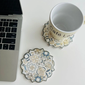 Detail of octagonal ceramic coasters with gold foil mandala patterns on a white desk