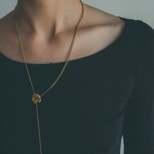 Detail of a vintage-style brass gold-plated Y-necklace with an irregular organic pendant