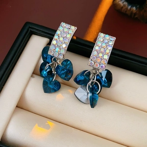 Macro shot of silver drop earrings with heart-shaped blue crystals in a jewelry box