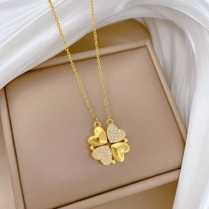 Detailed view of a gold clover necklace with heart-shaped pendants and sparkling crystals