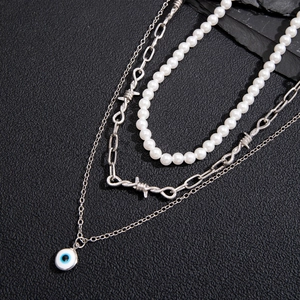Detail view of a three-layer necklace set with pearls and devil's eye pendant