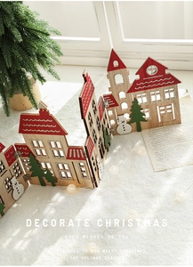 Miniature wooden Christmas house decoration with red roof and snowman on snowy windowsill
