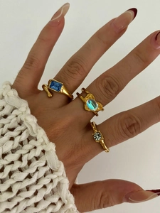 Detailed shot of three gold irregular rings featuring blue gems and opal-style stones