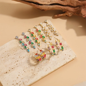 Elegant earrings collection with colorful cubic zirconia displayed on a beige stone base