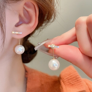Gros plan de boucles d'oreilles papillon dorées avec perles et zircons sur un mannequin