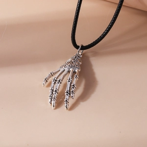 Macro shot of a silver vintage skeleton hand pendant on a black cord necklace
