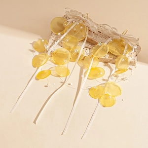 Detail of yellow shell-like discs and white ribbon bow on sweet long drop earrings