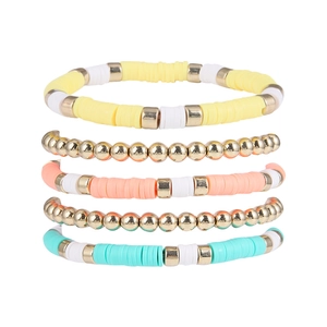 Détail de cinq bracelets bohèmes avec perles Heishi colorées et intercalaires en métal doré
