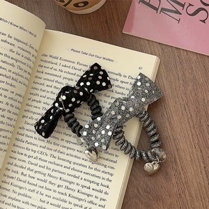 Sparkly sequin and polka dot bow hair ties with heart pendants on a vintage book