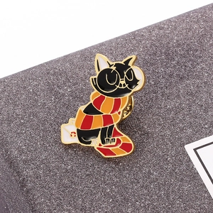 Detail shot of a cute black cat enamel pin with round glasses and a striped scarf