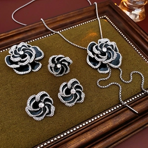 Detail of black enamel flower necklace and earrings set with crystal rhinestones