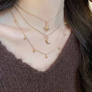Detail of layered gold necklace with star and moon pendants on a model's neck