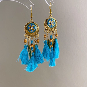 Detail of vintage bohemian dangle earrings with blue tassels and floral metal discs