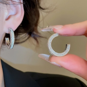 Close-up of silver C-shaped earrings with sparkling cubic zirconia on model's ear