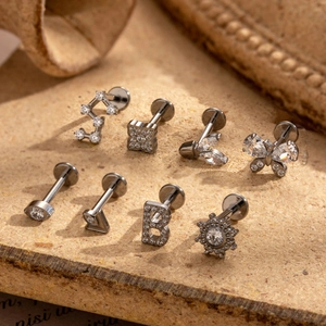 G23 titanium labret studs with zircon butterfly and leaf designs on vintage cork background