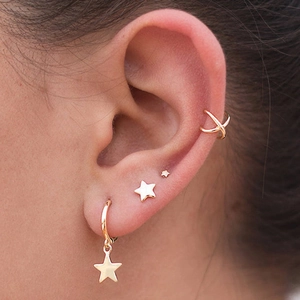 Luxurious gold-plated star earring set and cross ear cuff on a female model's ear