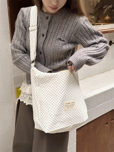 Close-up of blue polka dot canvas tote bag with adjustable strap and fabric label