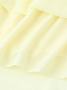 Detailed close-up of light yellow chiffon fabric with professional overlock edge stitching