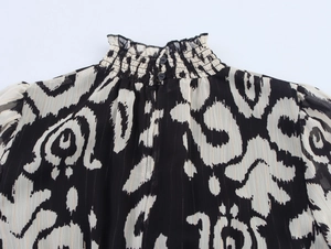 Close-up of smocked high collar and back button closure on black and white chiffon dress