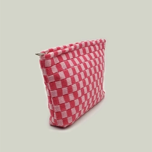 Detail of pink and white checkered knit makeup bag showing soft woven texture and metal zipper
