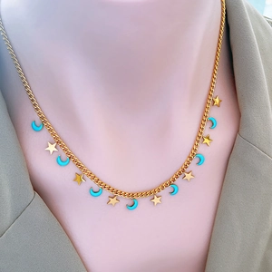 Chic gold-plated necklace with blue enamel moon and star charms shown on model