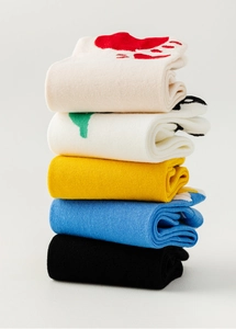 Detail view of five pairs of cotton socks in cream, white, yellow, blue, and black colors