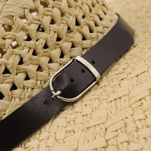 Close-up of hand-woven straw jazz hat featuring a black leather band and silver metal buckle