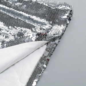 Macro shot of silver sequins fabric and white lining for backless evening gown detail
