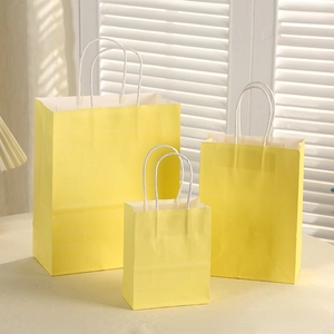 Three sizes of bright yellow gift bags with twisted handles shown in a domestic setting