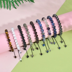 Detailed close-up of handmade woven beaded bracelets with natural stones on a pink display