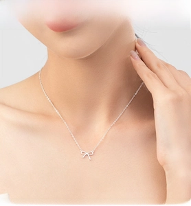 Gros plan d'un collier pendentif nœud en argent s925 porté au cou pour un style élégant