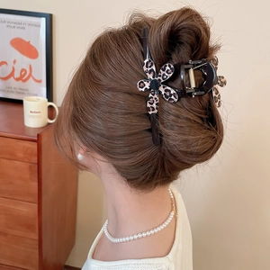 Close-up of leopard print flower hair claw clip on brunette hair in cozy setting