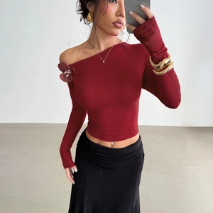 Burgundy off-shoulder long sleeve top with rose detail in a minimalist studio setting