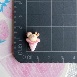 Close-up of pink resin ice cream cone charm with size reference on a metric cutting mat