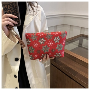 Détail d'une trousse à maquillage rouge de Noël avec motifs flocons tenue par un modèle
